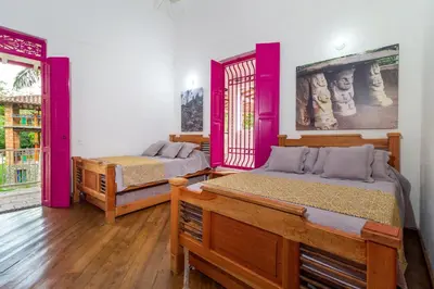 two beds in a room with pink walls and wooden floors at Casa Etnika in Jericó