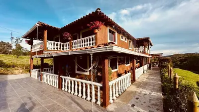 a wooden house with a porch and a balcony at Finca campestre mi retoño in Medellín