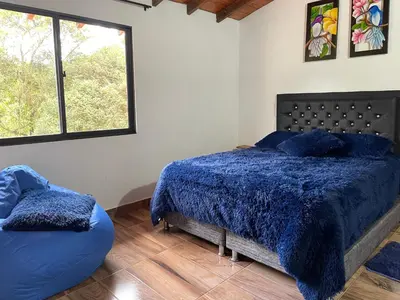 a bedroom with a blue bed and a window at Finca campestre mi retoño in Medellín