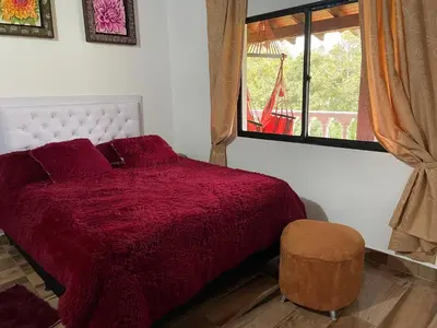 a bedroom with a red bed and a window at Finca campestre mi retoño in Medellín
