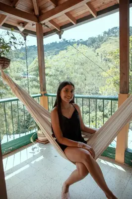a woman sitting in a hammock on a balcony at EcoHotel Casa Maria Parda in Cocorná