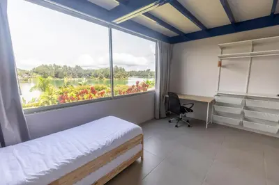 a bedroom with a bed and a desk and a large window at Cabaña familiar BANIA con vista del embalse al lado de la piedra in Guatapé