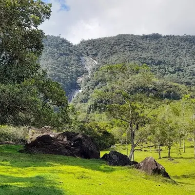 a green field with rocks and trees and a mountain at Casa Horizontes in San Carlos