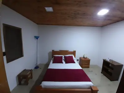 a bedroom with a large bed with red and white sheets at Casa Chute in Chinchiná