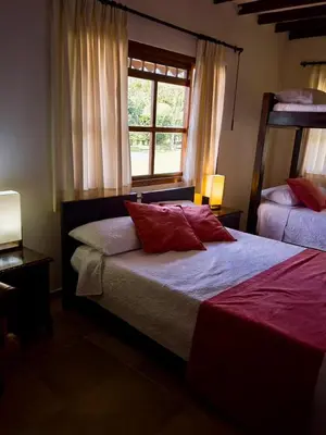 a bedroom with a bed with red pillows and a window at Casa Chute in Chinchiná