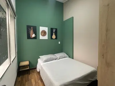 a bedroom with a bed and a green wall at Apartamento en Medellín sector del Poblado A101 By Roots Rentals in Medellín