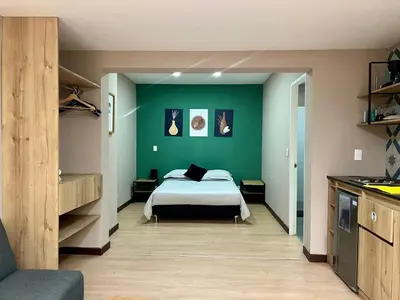 a bedroom with a bed and a green wall at Económico alojamiento en Medellín por días - A102 By Roots Rentals in Medellín
