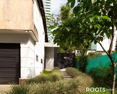 a white building with a garage and a tree at Alojamiento que permite mascota en Medellín A103 By Roots Rentals in Medellín