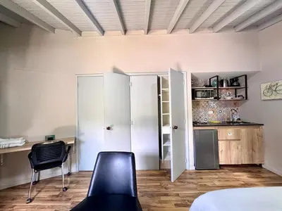 a room with a desk and a chair and a kitchen at Alojamiento que permite mascota en Medellín A103 By Roots Rentals in Medellín