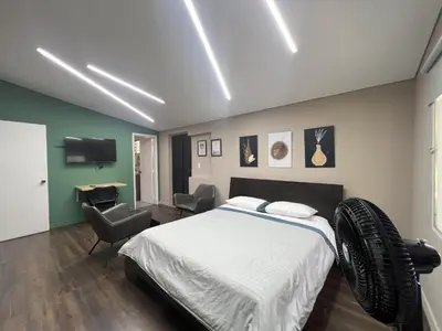 a bedroom with a bed and a tv and chairs at Hospedaje cerca a centro comercial de Santafé A104 By Roots Rentals in Medellín
