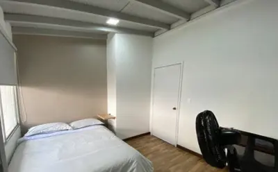 a bedroom with a bed and a white wall at Apartamento cerca al centro comercial Santafé A105 By Roots Rentals in Medellín