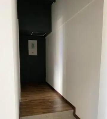 an empty hallway with a white wall and wood floors at Apartamento cerca al centro comercial Santafé A105 By Roots Rentals in Medellín