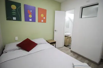 a bedroom with a bed with a red pillow on it at Cómodo aparta suite en zona Poblado Medellín M101 By Roots Rentals in Medellín