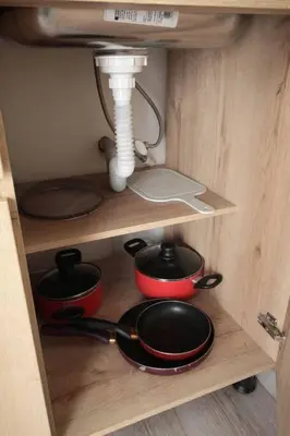 a shelf with pots and pans in a wooden cabinet at Hospedaje cerca a Provenza en el Poblado - M301 By Roots Rentals in Medellín