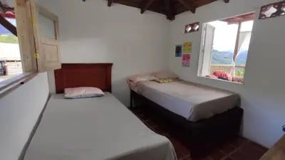two beds in a room with two windows at Casa La Martina disponible en Jardín Antioquia in Jardin