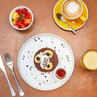 a plate of pancakes with whipped cream and a cup of coffee at Landmark Hotel in Medellín
