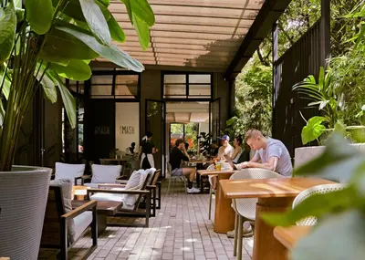 people sitting at tables in a restaurant with plants at Landmark Hotel in Medellín