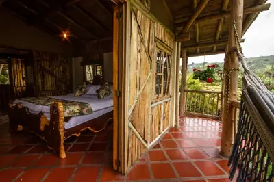 a bedroom with a bed in a room with a balcony at Hacienda Charrascal Coffe Farm in Manizales