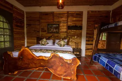 a log bedroom with a bed in a log cabin at Hacienda Charrascal Coffe Farm in Manizales