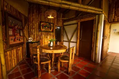 a table and chairs in a room with wooden walls at Hacienda Charrascal Coffe Farm in Manizales