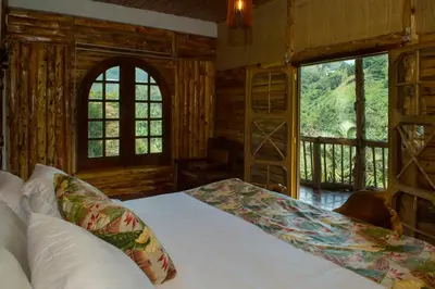 a bedroom with a bed in a room with windows at Hacienda Charrascal Coffe Farm in Manizales