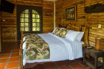 a bedroom with a bed in a log cabin at Hacienda Charrascal Coffe Farm in Manizales