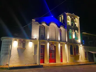 a white building with red doors at night at Casa Puerto Triunfo Dann in Puerto Triunfo