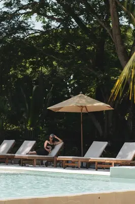 a woman sitting in a chair next to a pool at Casa Jacaranda Hotel Boutique -Cauca Viejo- Mayores de 14 años in Jericó
