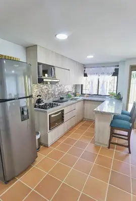 a kitchen with a stainless steel refrigerator and a table at Hermosa casa de campo en GUATAPÉ in Guatapé