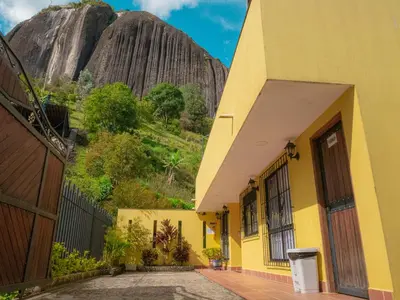 a yellow building with a mountain in the background at Hermosa casa de campo en GUATAPÉ in Guatapé