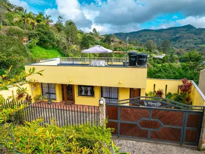 a yellow house with a wooden gate and a fence at Hermosa casa de campo en GUATAPÉ in Guatapé
