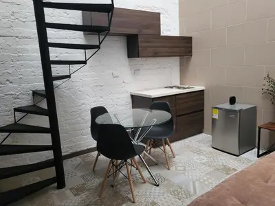a kitchen with a table and chairs and a spiral staircase at Casa Azul - Apartamentos Amoblados - in Manizales