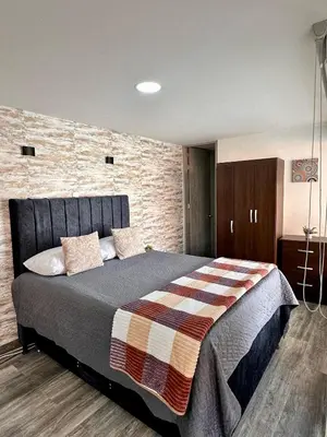 a bedroom with a large bed and a brick wall at Apartamentos cómodos en Milan zona G in Manizales