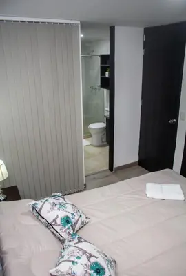 a bed with two pillows on it with a bathroom at Apartamentos cómodos en Milan zona G in Manizales