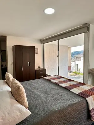 a bedroom with a large bed with a large window at Apartamentos cómodos en Milan zona G in Manizales
