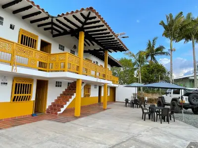 a yellow and white building with tables and chairs at Palmar de Jericó Suites in Jericó