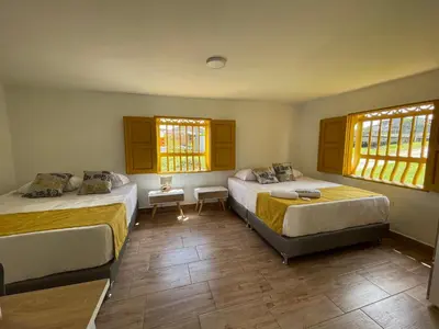 a bedroom with two beds and two windows at Palmar de Jericó Suites in Jericó