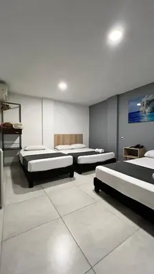 a room with three beds and a painting on the wall at Hotel Gran Conquistador 33 in Medellín