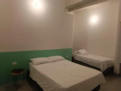two beds in a room with green and white walls at Aloja-T en Apartamento amoblado 6 con balcón Ciudad Bolivar in Ciudad Bolívar
