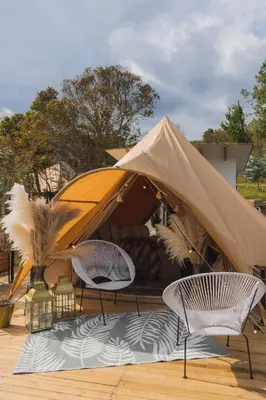 two chairs and a tent on a wooden deck at AKOA GLAMPING Eco-Luxury Hotel in Guarne