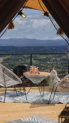 a table and chairs on a balcony with a view at AKOA GLAMPING Eco-Luxury Hotel in Guarne