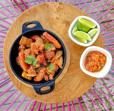a table with a pan of food and a bowl of vegetables at AKOA GLAMPING Eco-Luxury Hotel in Guarne