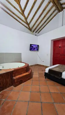 a bedroom with a tub and a bed and a tv at HOSTERÍA BRISAS DEL RÍO in Marinilla