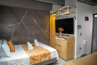 a room with a bed with a tv and a wall at Edificio Helena in Medellín