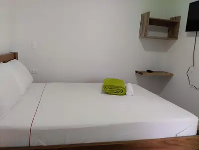 a white bed with a green towel sitting on it at HOTEL LA SELVA JARDIN in Jardin