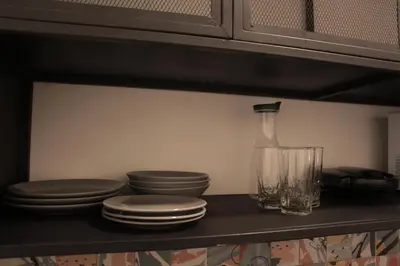 a shelf with plates and a bottle and a glass at Apartaestudio amueblado en Poblado FRN106 By Roots Rentals in Medellín