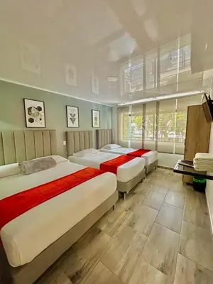 a bedroom with three beds and a television in it at Hotel Nakama in Medellín