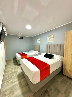 a bedroom with two beds with red and white sheets at Hotel Nakama in Medellín