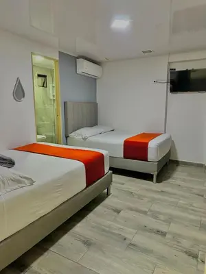 a bedroom with two beds and a television in it at Hotel Nakama in Medellín