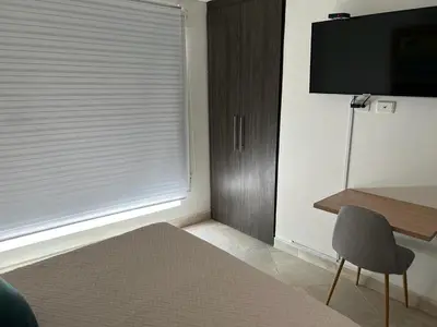 a room with a window with a television and a chair at Apartamento Amoblado laureles estadio in Medellín